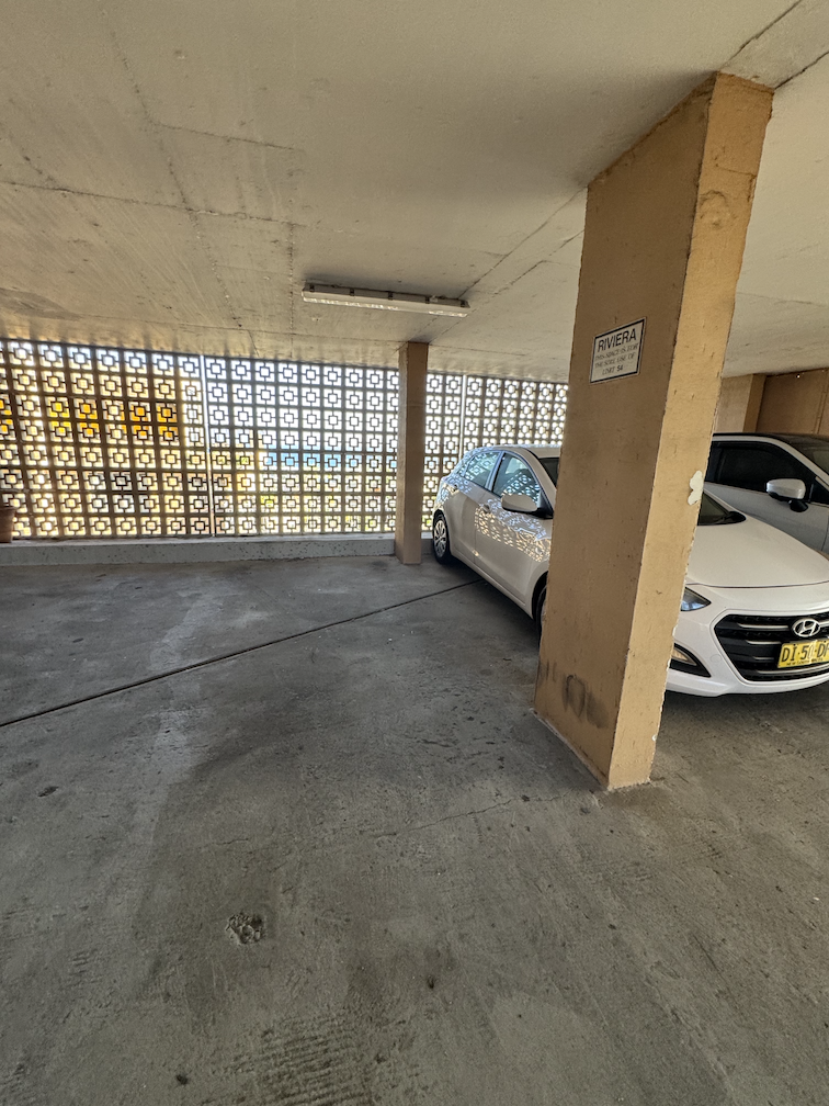 Cars parked beside the signed Unit 54 pillar in the North Bondi car park, shown for scale